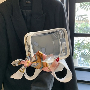 Detail of transparent PVC crossbody bag with white leather trim and floral silk scarf