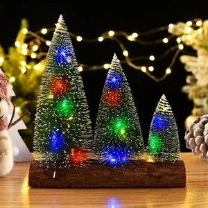 Close-up of three mini snow-dusted Christmas trees with glowing colorful LED lights