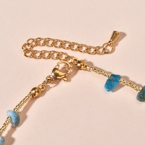 Macro detail of golden lobster clasp and extension chain on the blue stone beaded necklace