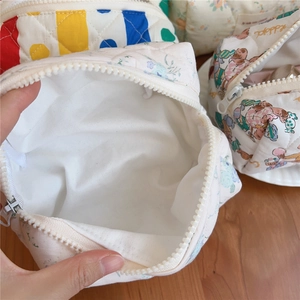 Detailed macro view of quilted cotton makeup bags with floral and bear patterns