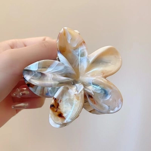 Détail de la pince à cheveux fleur à motif marbré avec ressort en métal robuste