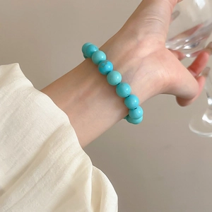 Detail of turquoise beaded stretch bracelet with natural stone texture on a model's wrist