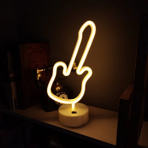 Detail of guitar-shaped neon sign with warm yellow light on a white circular base