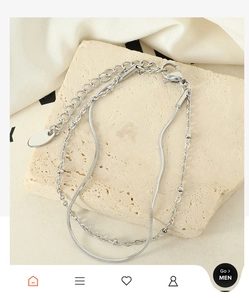 Detail view of double-layer silver snake chain bracelet on a decorative stone base