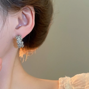 Vue détaillée de boucles d'oreilles argentées en C avec texture lave sur un modèle