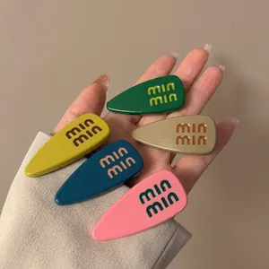 Set of five colorful droplet hair clips with artistic lettering in vibrant saturated tones