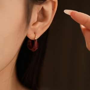 Detail shot of the deep red resin U-shaped earring with elegant gold plated accents