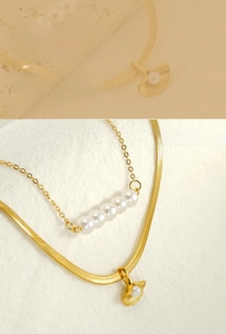 Detail of layered gold ginkgo leaf necklace with elegant pearls and snake chain