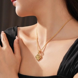 Gros plan d'un collier doré avec pendentif trèfle texturé porté par un mannequin