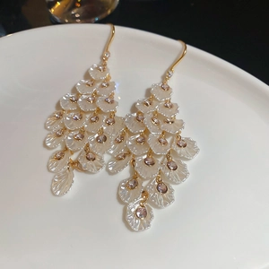 Close-up of elegant acrylic flower earrings with gold tassels and crystal accents