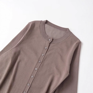 Cardigan in maglia marrone con girocollo e dettagli di bottoni su fondo chiaro