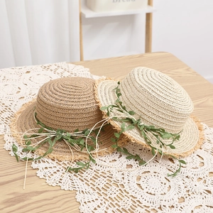 Dettaglio di cappelli di paglia in rafia con viti di foglie e fiocchi di corda