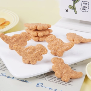 Modèles réalistes de nuggets de poulet dinosaures brun doré disposés sur une assiette blanche