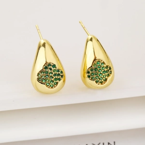 Macro shot of gold teardrop earrings featuring a four-leaf clover with green zircon inlay