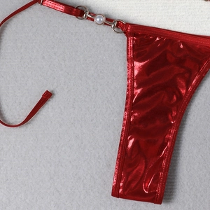 Macro detail of red shiny bikini bottom with metal ring and pearl side tie decoration