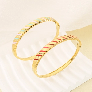 Macro detail of 18K gold plated bangle with wavy texture and colorful enamel stripes