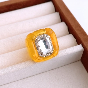 Close-up of yellow resin hexagonal ring with large crystal and small diamond accents