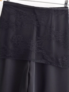 Detail shot of black lace stitching on satin trousers showing mesh texture and high craftsmanship