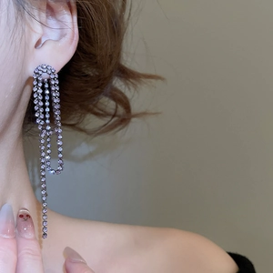 Close-up of elegant long purple rhinestone tassel earrings worn on a female model