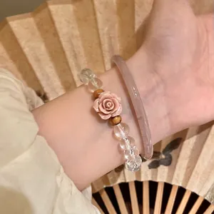 Detailed shot of a beaded bracelet with a pink rose charm and light purple bangle
