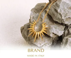 Close-up of a golden sunburst pendant on gray rock, showcasing polished steel texture