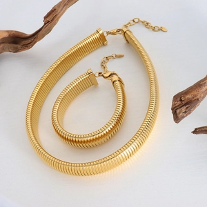 Polished gold metal twisted snake chain necklace and bracelet set on white background