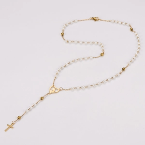 Vue détaillée du collier de perles avec pendentif croix dorée et breloque en cœur