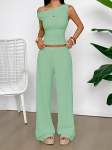 Detail of mint green crinkled fabric two-piece set with one-shoulder top and wide-leg pants
