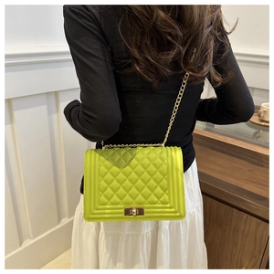 Close-up of vibrant lime green quilted chain bag worn by a model in a minimalist setting