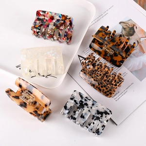 Square acetate hair claws in various patterns like marble and leopard on a tray