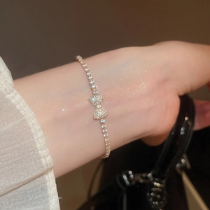 Close-up of elegant gold bow bracelet with pavé cubic zirconia worn on a wrist