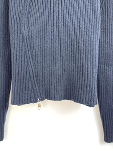 Detail of navy ribbed knit sweater featuring a modern diagonal metal zipper at the hem