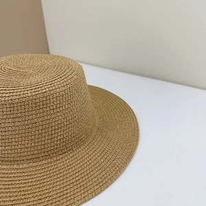 Close-up of fine spiral weave pattern on a natural straw hat with flat brim detail