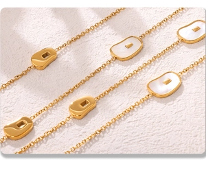 Close-up of gold chain necklace featuring natural white shell inlays and irregular metal blocks