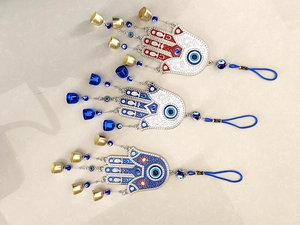 Close-up of three Hamsa Hand charms with evil eye motifs in silver and gold finishes