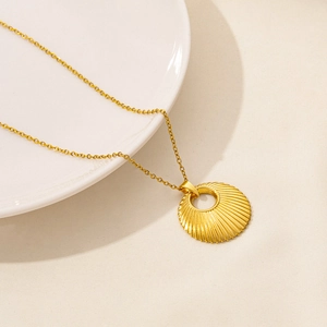 Macro detail of a 18k gold plated sunburst pendant necklace on a white porcelain dish