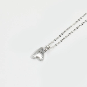Detailed macro view of silver letter A pendant with heart cutout and grainy metal texture