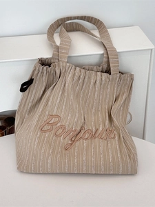 Minimalist striped canvas tote bag with Bonjour embroidery shown in a home setting
