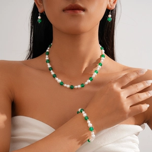Three-piece jewelry set with green agate and white pearls on an elegant female model