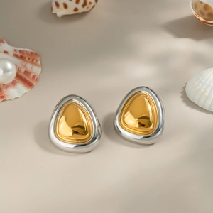 Two-tone silver and gold triangular stud earrings on a beach-themed background