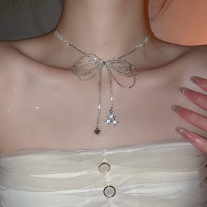 Detail of silver bow necklace with crystal beads and heart pendant on model