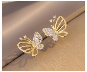 Macro shot of asymmetric gold butterfly earrings with micro-set cubic zirconia details