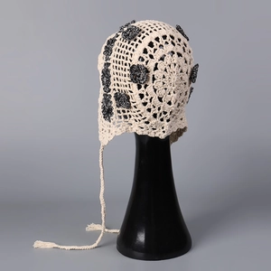 Macro detail of handmade crochet floral hat showing beige hollow texture and black flowers