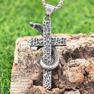 Vintage silver snake pendant wrapped around a cross with detailed scales on tree bark