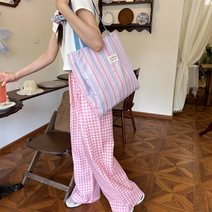 Dettaglio di una grande borsa tote a bolle a righe rosa e blu portata a spalla da donna