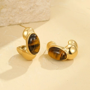 Detail of vintage C-shaped gold earrings inlaid with brown tiger eye stone on stone