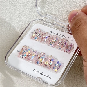 Short handmade press-on nails with colorful glitter in a clear box with size labels