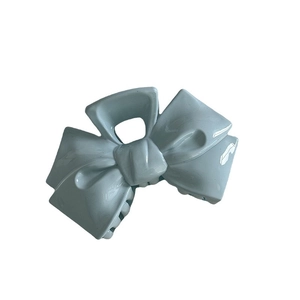 Light blue bow-shaped hair claw clip in glossy plastic for elegant updos on white background