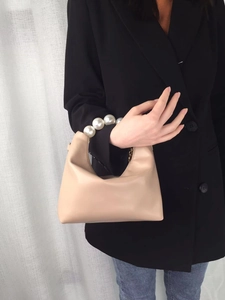 Detailed view of beige PU leather handbag featuring elegant pearl handle and metal chain