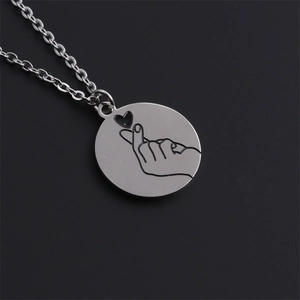 Collier en acier inoxydable argenté avec pendentif rond geste de cœur sur fond noir
